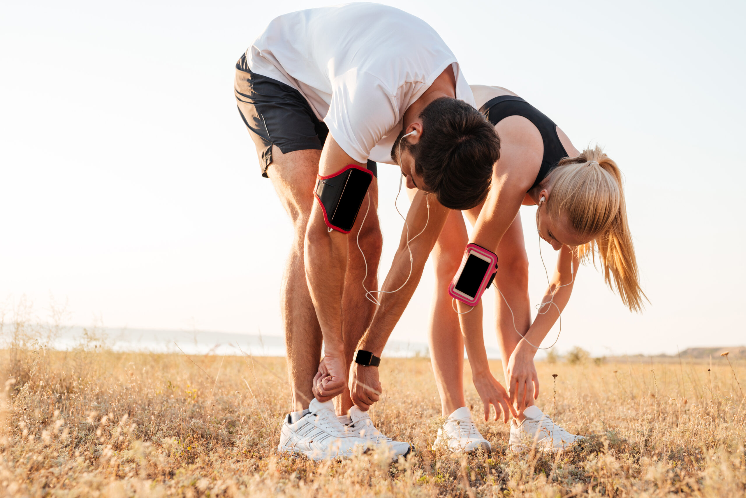 Young couple tying their shoes and getting ready for running and working out together outdoors